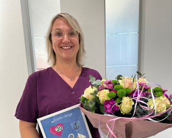 Mitarbeiterin mit Blumenstrauß zum 20. Jubiläum