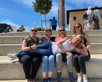Mitarbeiterinnen und Zahnärztin posieren auf einer Treppe
